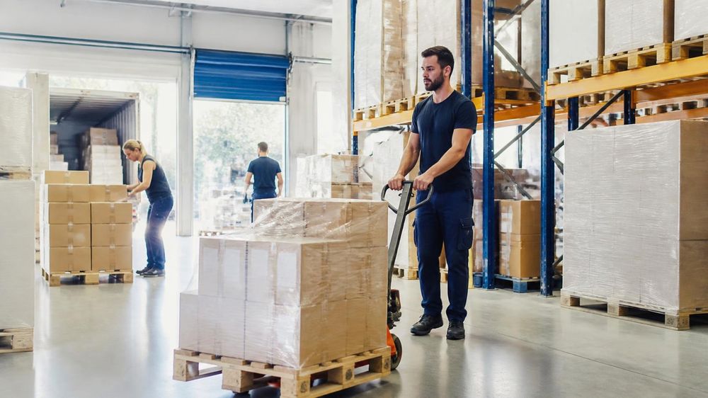 Warehouse worker moving a wrapped pallet for loading